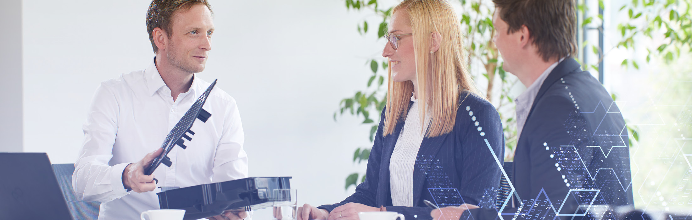 Drei Personen sitzen an einem Tisch und reden.