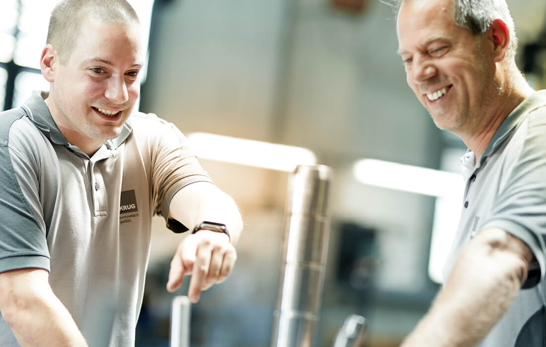 Zwei lächelnde KRUG-Mitarbeiter.